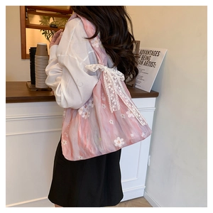 Détail d'un sac cabas fleuri rose avec un grand nœud en dentelle blanche brodé