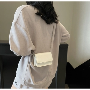 Close-up of white crocodile pattern mini crossbody bag with silver chain on model