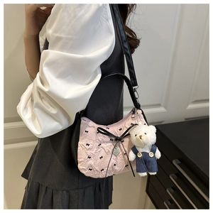 Vue détaillée du sac sous le bras rose matelassé avec nœud noir et breloque ours