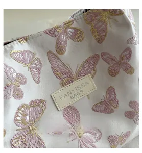 Detail of pink butterfly jacquard fabric and FANYISSA leather label on the shoulder bag