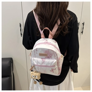 Detailed shot of white and pink floral backpack with a cute plush monster charm