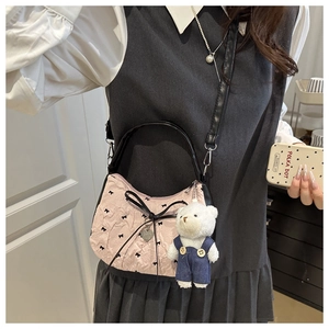 Détail d'un sac à main plissé rose avec nœuds noirs et pendentif d'ours en peluche