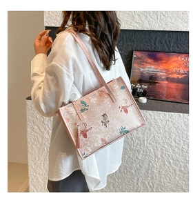 Detail of pink embroidered tote bag with butterfly patterns and tassel accessory
