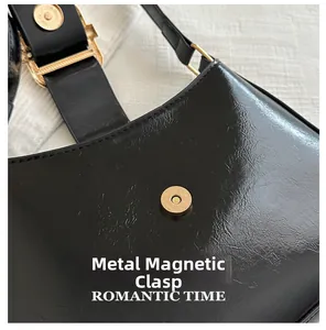 Close-up of black glossy leather bag with premium gold magnetic hardware buckle closure