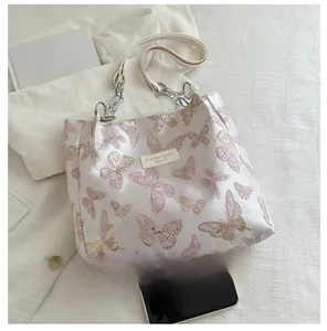Detail of elegant butterfly embroidery on satin tote bag with metallic chain strap