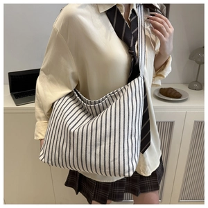 Détail du grand sac cabas en toile à rayures noires et blanches porté à l'épaule