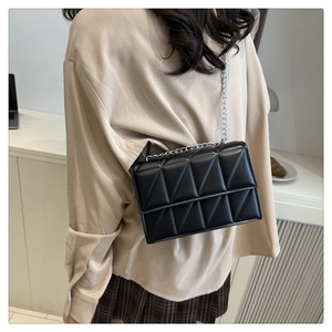 Detailed view of black quilted crossbody bag with silver chain strap and geometric stitching
