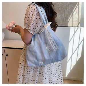 Détail du sac cabas en mousseline florale avec nœud en dentelle et broderie de fleurs
