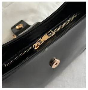 Detail of premium black leather handbag featuring smooth gold zipper and magnetic snap closure