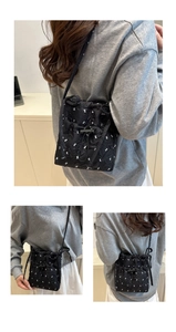 Detail of black quilted shoulder bag featuring white cartoon patterns and drawstring closure