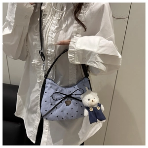 Vue détaillée du sac croissant à rayures avec nœud noir et porte-clé ours en peluche