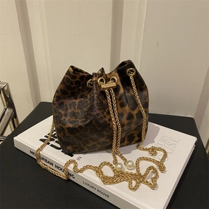 Detail of leopard print bucket bag featuring gold chain and elegant pearl accents