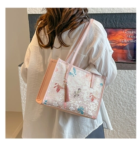 Detail of pink embroidered tote bag with butterfly patterns and silk tassel accessory