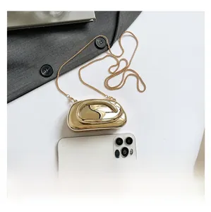 Top view of gold mirror finish pebble clutch bag next to a smartphone for size reference