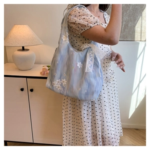 Détail de sac cabas bleu clair avec broderies florales 3D et ruban en dentelle chic