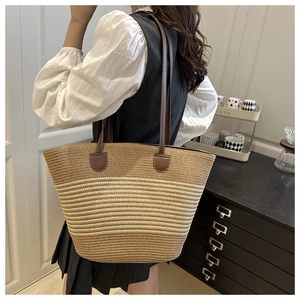Close-up of woven straw tote bag with brown leather shoulder straps and striped texture