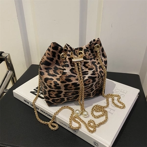 Detail of leopard print bucket bag featuring golden chain and large pearl drawstring charms