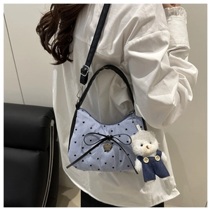 Détail du sac sous l'épaule à rayures bleues avec nœud noir et charmant ours en peluche