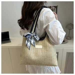 Detail of a large woven tote bag with blue floral scarf and black leather shoulder straps