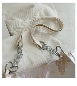 Macro shot of faux leather handles with silver metal chains on a butterfly tote bag
