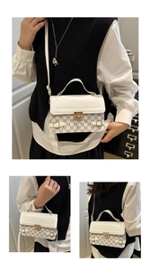 Detailed view of white canvas and leather handbag with M-pattern and gold clasp hardware
