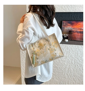Detailed view of floral jacquard tote bag with light green silk tassel and white leather strap