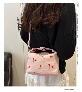 Detail of pink corduroy handbag featuring red cherry embroidery and adjustable strap