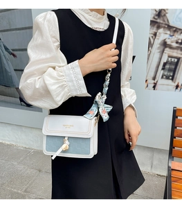 Detail view of contrast color crossbody bag with silk scarf handle and heart pendant