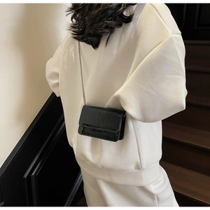 Close-up of black glossy patent leather mini bag with elegant silver chain strap