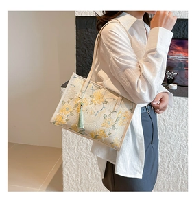 Detail of elegant jacquard handbag with yellow floral patterns and green tassel
