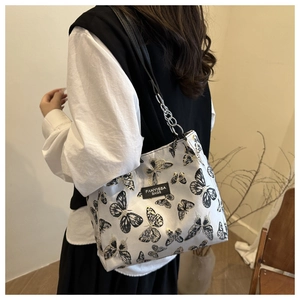 Detailed view of white shoulder bag with butterfly patterns and silver chain strap