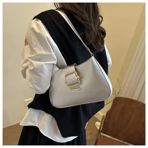 Detail view of silver shoulder bag with large gold buckle on model for casual wear