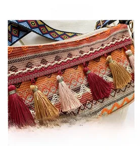 Détail du sac tissé bohème aux motifs géométriques et franges à pompons colorés