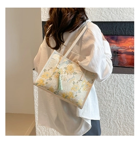 Detailed view of the woven brocade fabric with floral embroidery and silk tassel on the tote
