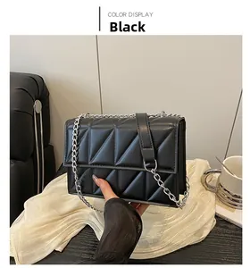 Detail of black quilted crossbody bag with triangle stitching and silver chain strap