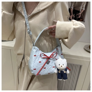 Détail du sac bandoulière bleu clair avec nœuds rouges et pendentif d'ours mignon