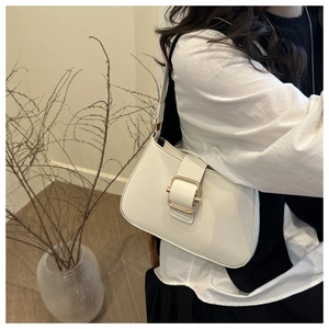 Close-up of white leather underarm bag featuring a stylish gold metal square buckle design