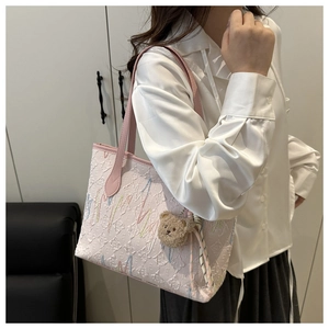 Detailed view of pink embossed canvas tote bag with brown bear plush pendant charm