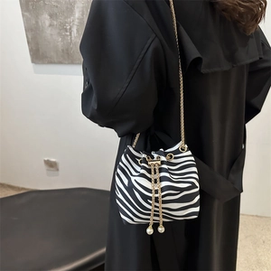 Detail of zebra pattern bucket bag with gold chain and pearl drawstring charms