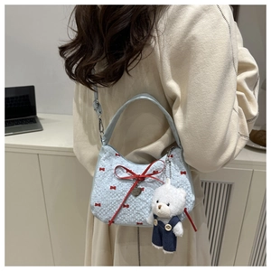 Détail du sac matelassé bleu clair avec nœuds rouges et charmant ours en peluche