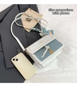 White and blue flap crossbody bag with scarf handle and phone for size reference