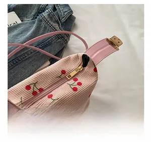 Close-up of smooth golden zipper on pink corduroy handbag with red cherry pattern