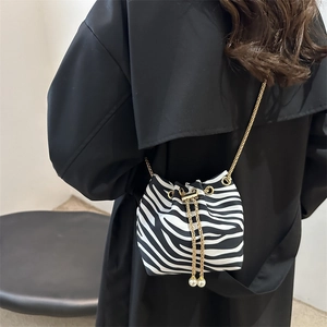 Detail of zebra pattern bucket bag with gold chain strap and pearl drawstring charms