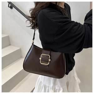 Detail of dark brown vintage shoulder bag with gold square buckle worn with casual outfit