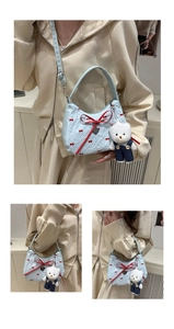 Détail du sac croissant bleu avec nœuds rouges, perles et pendentif d'ours mignon