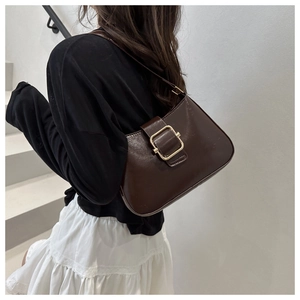 Close-up of a vintage dark brown shoulder bag featuring a large golden square buckle