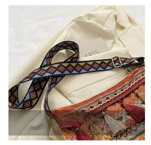 Détail du sac tissé bohème avec bandoulière jacquard géométrique et pompons colorés