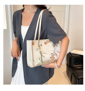 Detail of cream tote bag featuring traditional Chinese bird and fruit art with tassel