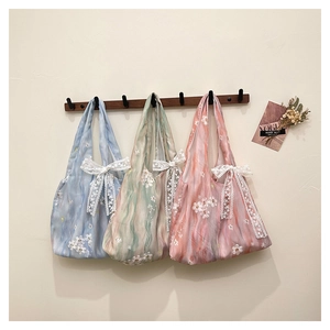 Détail de broderie florale et de grands nœuds en dentelle sur des sacs fourre-tout