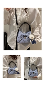 Détail du sac sous l'aisselle à rayures bleu clair avec nœud noir et breloque ours